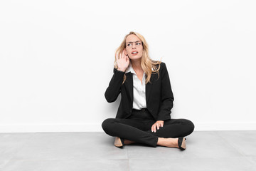 young blonde woman looking serious and curious, listening, trying to hear a secret conversation or...