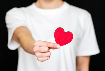 man holds red heart in his hands on the background of light clothes