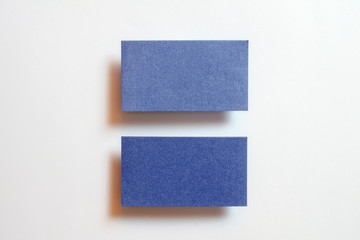 Two blue blank matt linear textured horizontal position business cards flying and isolated on white paper background, us standard size 3.5 x 2 inches, real non professional studio photo.