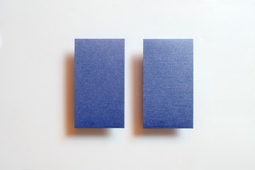 Two blue blank matt linear textured vertical position business cards flying and isolated on white paper background, us standard size 3.5 x 2 inches, real non professional studio photo.