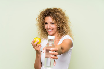 Young blonde woman with curly hair with an apple and with a bottle of water