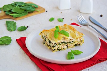 Lasagna with salmon and spinach on a clay plate on a light concrete background. Italian food. Pasta Recipes