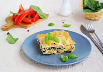 Lasagna with salmon and spinach on a gray clay plate on a light concrete background. Italian food. Pasta Recipes