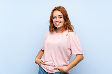 Teenager redhead girl over isolated blue background laughing