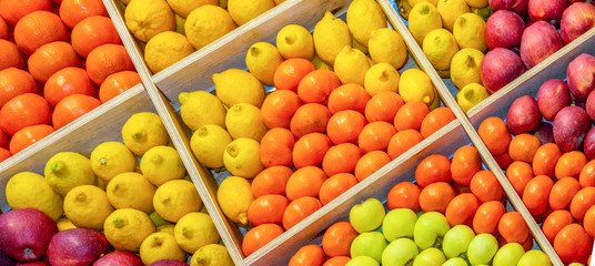 Many different fruits apples lemons tangerines lie in boxes and form an ornament, pattern. View from above