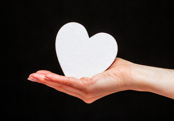 Obraz premium man holds white heart in his hands on the black background