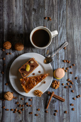 Cup of coffee and two slices of cake and macaroons on the plate on wooden table