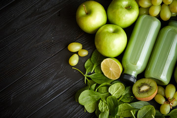 Mixed green fruits and vegetables placed on black wooden table