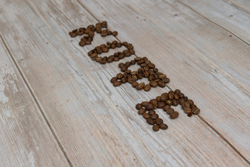 Russian word coffee made from black coffee beans on brown wooden table, roasted cofee, top view from above. Translations for non-English text: 