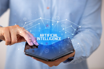 Businessman holding a foldable smartphone with ARTIFICIAL INTELLIGENCE inscription, new technology concept