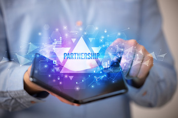 Businessman holding a foldable smartphone with PARTNERSHIP inscription, business concept