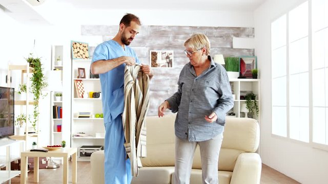 Male Nurse Helping Senior Woman Getting Dressed