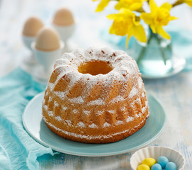 Easter yeast cake sprinkled with powdered sugar on a turquoise plate. Traditional Easter dessert in Poland