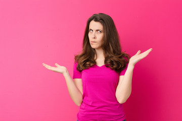 young pretty woman shrugging with a dumb, crazy, confused, puzzled expression, feeling annoyed and...