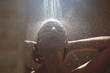 Authentic naked blonde girl takes a shower, washes sexy body with water drops in bathroom, enjoys with eyes closed