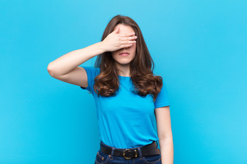 young pretty woman covering eyes with one hand feeling scared or anxious, wondering or blindly...