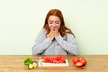 Teenager redhead girl with vegetables in a table