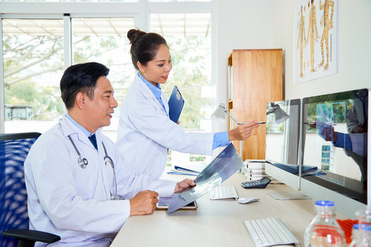 Horizontal shot of two Asian doctors coworking on new medical case in office