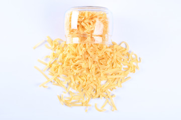 Glass jar filled with dry rotini yellow pasta over isolated white background