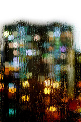 Naklejka premium Glass window with raindrops on the background of blurred lights of the city.