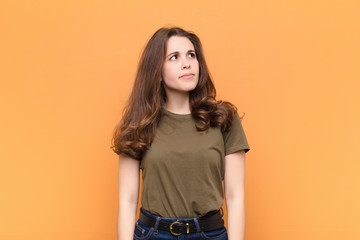 young pretty woman with a worried, confused, clueless expression, looking up to copy space,...