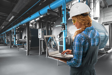  Attractive Caucasoid engineer woman with laptop inspect modern industrial gas boiler room. Heating...