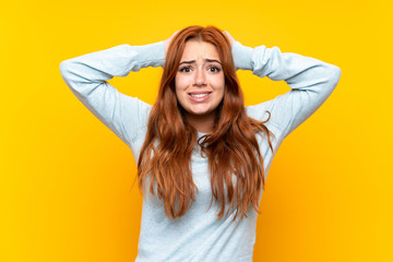 Teenager redhead girl over isolated yellow background frustrated and takes hands on head