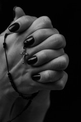 Praying hands with a cross in black and white