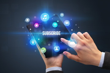 Businessman holding a foldable smartphone with SUBSCRIBE inscription, social media concept