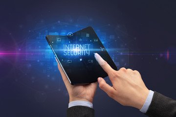 Businessman holding a foldable smartphone with INTERNET SECURITY inscription, cyber security concept