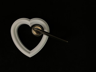 Heart with a door handle on a black background. The white heart opens with a hand. Concept: closed heart.