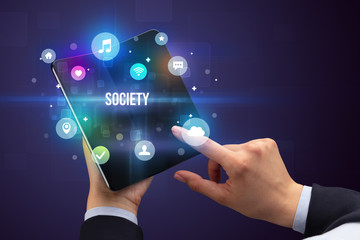 Businessman holding a foldable smartphone with SOCIETY inscription, social media concept