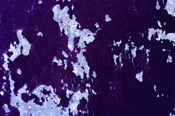 Texture of peeling old purple paint on a concrete wall.