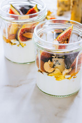 Dessert of sour cream, vanilla, figs, nuts, honey and blue cheese in a glass on a marble background