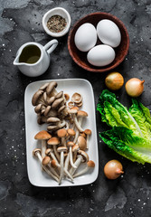 Ingredients for cooking healthy breakfast, brunch - egg, mixed mushrooms and green salad on a dark background, top view