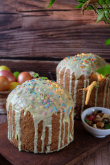 Easter table with two cakes and painted Easter eggs with a birch branch in a vase.