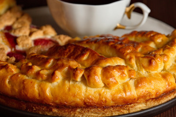  Delicious lemon pie is on a large white plate. Close up. Very tasty homemade cakes. Cup of fragrant tea.