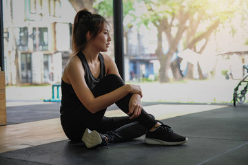 Fototapeta na wymiar Relaxing after training. Young asian woman sitting and relaxing after her workout at gym.