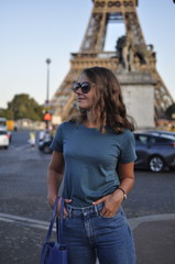 Fototapeta na wymiar young Caucasian long-haired woman in Paris against the Eiffel Tower in summer. Tourist walk in Europe.