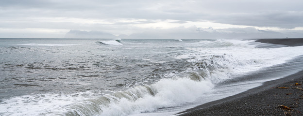 Panorama of waves crash ashore on Hvalnes beach with black lava sand on Hvalnes peninsula in southern Iceland. Traveling and photgraphy concept. Vestrahorn in the background.