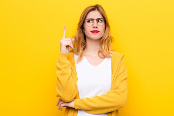 young pretty blonde woman feeling like a genius holding finger proudly up in the air after...