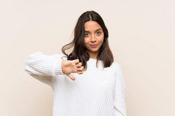 Young brunette woman with white sweater over isolated background showing thumb down sign
