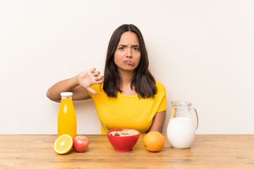 Young brunette girl having breakfast milk showing thumb down sign