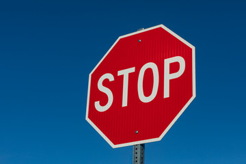 Obraz premium Closeup angled view of reflective stop sign isolated on deep blue sky background