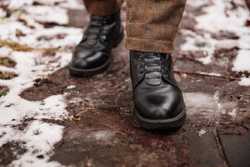 Female feet in black boots, winter walking in snow