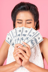 Successful beautiful Asian business young woman feel happy holding money US dollar bills in hand on pink background , business concept