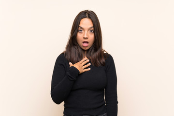 Young brunette woman with white sweater over isolated background surprised and shocked while...