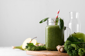 Freshly prepared jar of green smoothie, close up. Fresh vegetable smoothie on a light background. Vegetable smoothie with spinach and kale cabbage.