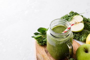 Freshly prepared jar of green smoothie, close up. Fresh vegetable smoothie on a light background. Vegetable smoothie with spinach and kale cabbage.