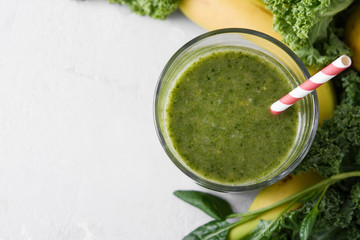 Freshly prepared glass of green smoothie, close-up. Fresh vegetable smoothie on a light background. Vegetable smoothie with spinach and kale cabbage.